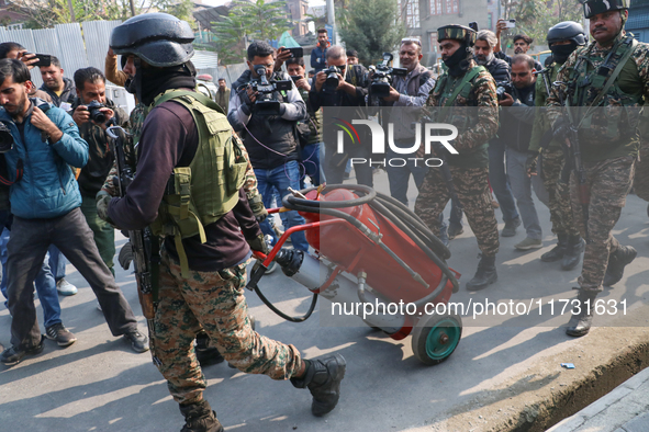 Indian paramilitary troopers carry a flamethrower as they move towards an encounter site in Srinagar, Indian Administered Kashmir, on Novemb...