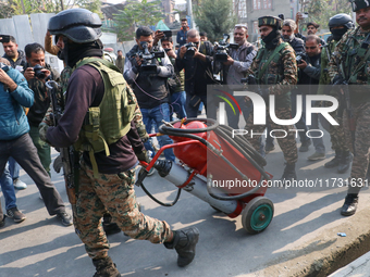 Indian paramilitary troopers carry a flamethrower as they move towards an encounter site in Srinagar, Indian Administered Kashmir, on Novemb...