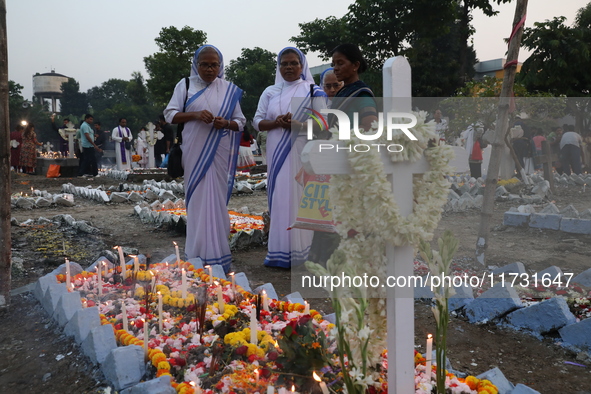 People light candles and lay flowers on the graves of their relatives at a cemetery during All Souls Day in Kolkata, India, on November 2, 2...