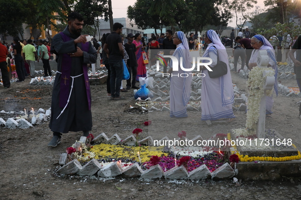 People light candles and lay flowers on the graves of their relatives at a cemetery during All Souls Day in Kolkata, India, on November 2, 2...