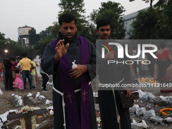 People light candles and lay flowers on the graves of their relatives at a cemetery during All Souls Day in Kolkata, India, on November 2, 2...