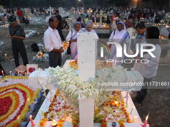 People light candles and lay flowers on the graves of their relatives at a cemetery during All Souls Day in Kolkata, India, on November 2, 2...