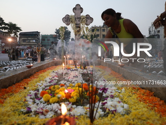 People light candles and lay flowers on the graves of their relatives at a cemetery during All Souls Day in Kolkata, India, on November 2, 2...