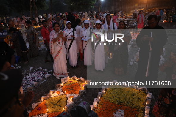 People light candles and lay flowers on the graves of their relatives at a cemetery during All Souls Day in Kolkata, India, on November 2, 2...