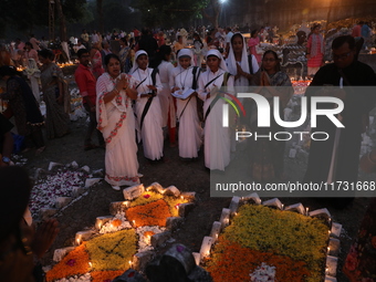 People light candles and lay flowers on the graves of their relatives at a cemetery during All Souls Day in Kolkata, India, on November 2, 2...