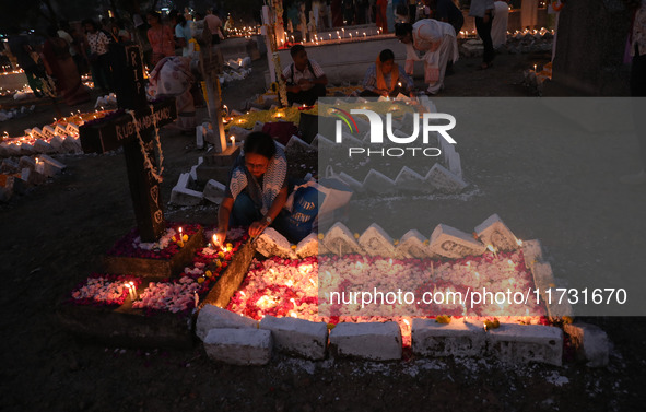 People light candles and lay flowers on the graves of their relatives at a cemetery during All Souls Day in Kolkata, India, on November 2, 2...