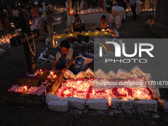 People light candles and lay flowers on the graves of their relatives at a cemetery during All Souls Day in Kolkata, India, on November 2, 2...