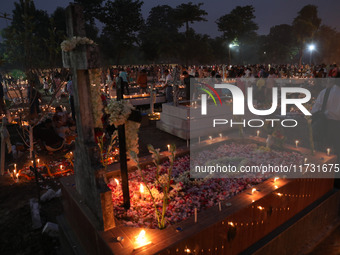 People light candles and lay flowers on the graves of their relatives at a cemetery during All Souls Day in Kolkata, India, on November 2, 2...