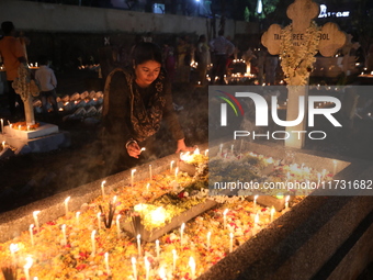 People light candles and lay flowers on the graves of their relatives at a cemetery during All Souls Day in Kolkata, India, on November 2, 2...