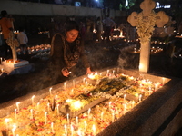 People light candles and lay flowers on the graves of their relatives at a cemetery during All Souls Day in Kolkata, India, on November 2, 2...