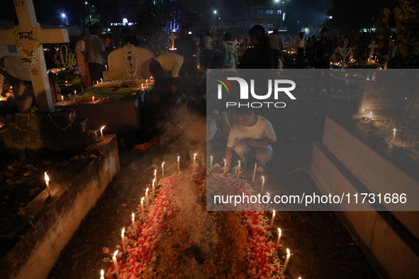 People light candles and lay flowers on the graves of their relatives at a cemetery during All Souls Day in Kolkata, India, on November 2, 2...