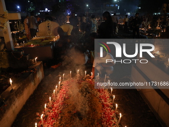 People light candles and lay flowers on the graves of their relatives at a cemetery during All Souls Day in Kolkata, India, on November 2, 2...