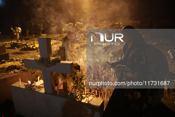 People light candles and lay flowers on the graves of their relatives at a cemetery during All Souls Day in Kolkata, India, on November 2, 2...