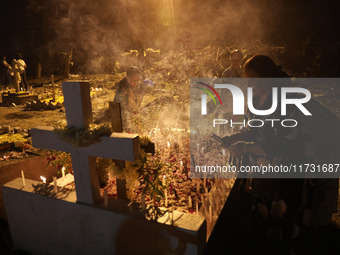 People light candles and lay flowers on the graves of their relatives at a cemetery during All Souls Day in Kolkata, India, on November 2, 2...