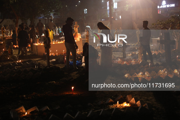 People light candles and lay flowers on the graves of their relatives at a cemetery during All Souls Day in Kolkata, India, on November 2, 2...