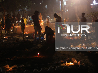 People light candles and lay flowers on the graves of their relatives at a cemetery during All Souls Day in Kolkata, India, on November 2, 2...