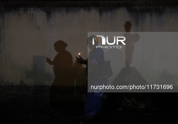 People light candles and lay flowers on the graves of their relatives at a cemetery during All Souls Day in Kolkata, India, on November 2, 2...