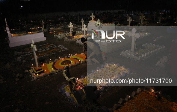 People light candles and lay flowers on the graves of their relatives at a cemetery during All Souls Day in Kolkata, India, on November 2, 2...