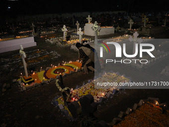 People light candles and lay flowers on the graves of their relatives at a cemetery during All Souls Day in Kolkata, India, on November 2, 2...