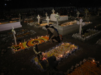 People light candles and lay flowers on the graves of their relatives at a cemetery during All Souls Day in Kolkata, India, on November 2, 2...