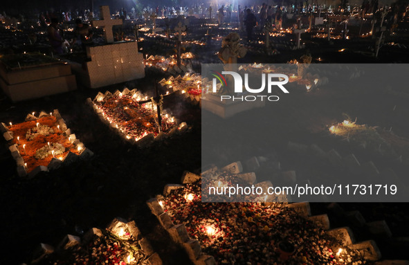 People light candles and lay flowers on the graves of their relatives at a cemetery during All Souls Day in Kolkata, India, on November 2, 2...