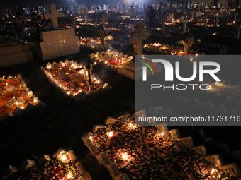 People light candles and lay flowers on the graves of their relatives at a cemetery during All Souls Day in Kolkata, India, on November 2, 2...