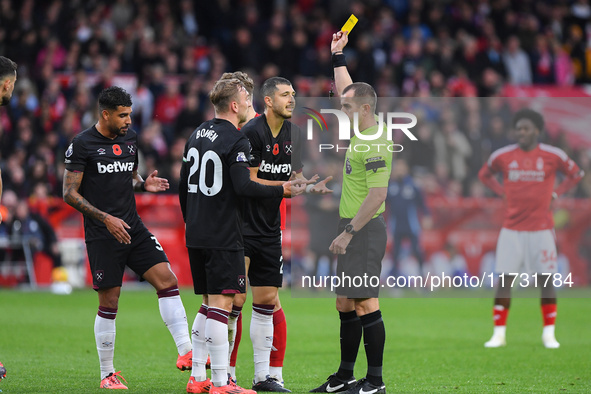 Referee Peter Bankes shows a yellow card to Guido Rodriguez of West Ham United during the Premier League match between Nottingham Forest and...