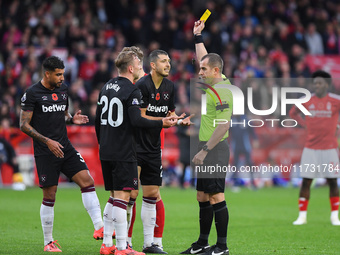 Referee Peter Bankes shows a yellow card to Guido Rodriguez of West Ham United during the Premier League match between Nottingham Forest and...