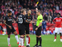 Referee Peter Bankes shows a yellow card to Guido Rodriguez of West Ham United during the Premier League match between Nottingham Forest and...