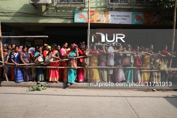 Hindu devotees stand in a queue to receive rice as offerings distributed by the temple authority on the occasion of the Annakut festival in...