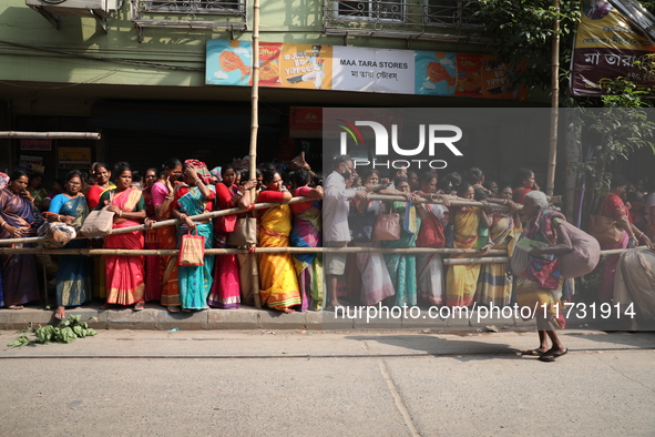 Hindu devotees stand in a queue to receive rice as offerings distributed by the temple authority on the occasion of the Annakut festival in...