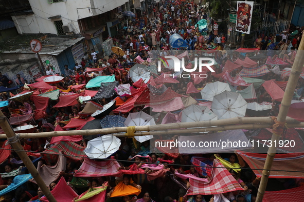 Hindu devotees hold up clothes and umbrellas to receive rice as offerings distributed by the temple authority on the occasion of the Annakut...