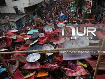 Hindu devotees hold up clothes and umbrellas to receive rice as offerings distributed by the temple authority on the occasion of the Annakut...