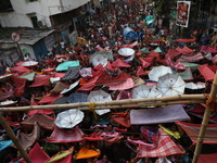 Hindu devotees hold up clothes and umbrellas to receive rice as offerings distributed by the temple authority on the occasion of the Annakut...