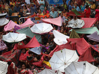 Hindu devotees hold up clothes and umbrellas to receive rice as offerings distributed by the temple authority on the occasion of the Annakut...