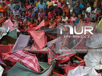 Hindu devotees hold up clothes and umbrellas to receive rice as offerings distributed by the temple authority on the occasion of the Annakut...