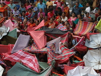 Hindu devotees hold up clothes and umbrellas to receive rice as offerings distributed by the temple authority on the occasion of the Annakut...