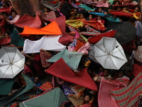 Hindu devotees hold up clothes and umbrellas to receive rice as offerings distributed by the temple authority on the occasion of the Annakut...