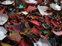 Hindu devotees hold up clothes and umbrellas to receive rice as offerings distributed by the temple authority on the occasion of the Annakut...