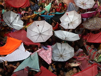 Hindu devotees hold up clothes and umbrellas to receive rice as offerings distributed by the temple authority on the occasion of the Annakut...