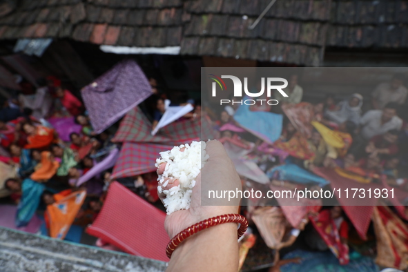 Hindu devotees hold up clothes to receive rice as offerings distributed by the temple authority on the occasion of the Annakut festival in K...