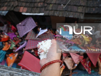 Hindu devotees hold up clothes to receive rice as offerings distributed by the temple authority on the occasion of the Annakut festival in K...