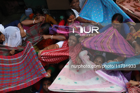 Hindu devotees hold up clothes to receive rice as offerings distributed by the temple authority on the occasion of the Annakut festival in K...