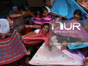 Hindu devotees hold up clothes to receive rice as offerings distributed by the temple authority on the occasion of the Annakut festival in K...