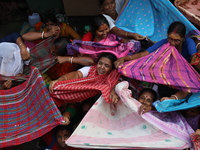 Hindu devotees hold up clothes to receive rice as offerings distributed by the temple authority on the occasion of the Annakut festival in K...