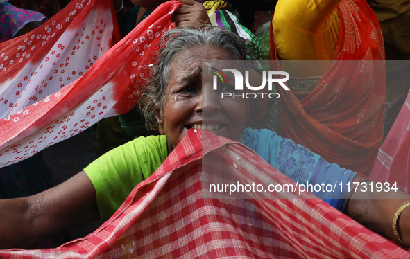 Hindu devotees hold up clothes to receive rice as offerings distributed by the temple authority on the occasion of the Annakut festival in K...