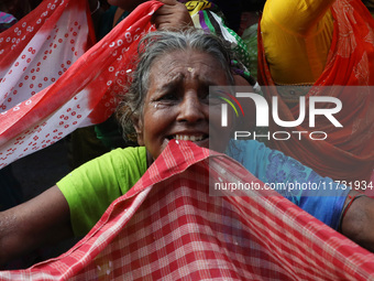 Hindu devotees hold up clothes to receive rice as offerings distributed by the temple authority on the occasion of the Annakut festival in K...