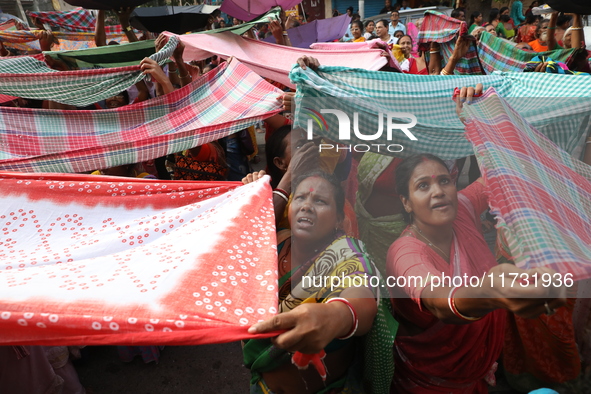 Hindu devotees hold up clothes to receive rice as offerings distributed by the temple authority on the occasion of the Annakut festival in K...