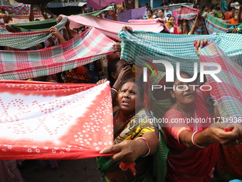 Hindu devotees hold up clothes to receive rice as offerings distributed by the temple authority on the occasion of the Annakut festival in K...