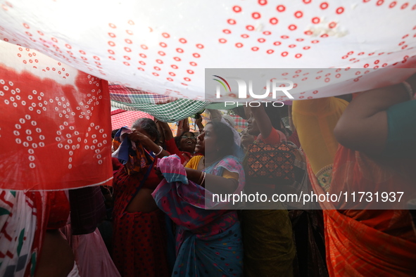 Hindu devotees hold up clothes to receive rice as offerings distributed by the temple authority on the occasion of the Annakut festival in K...